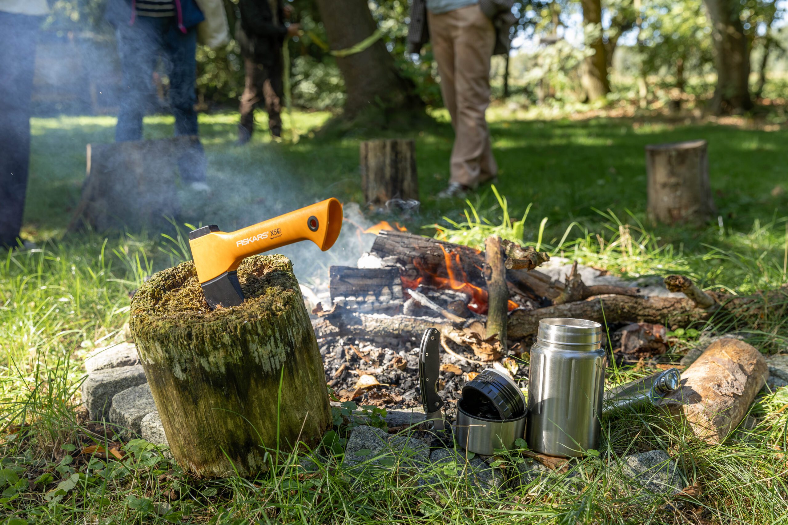 Kampvuur met bijl en thermosfles tijdens de outdoor ochtend